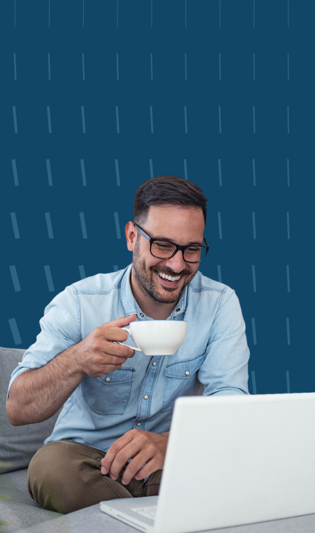 Uma pessoa feliz segurando uma caneca e olhando para o notebook.